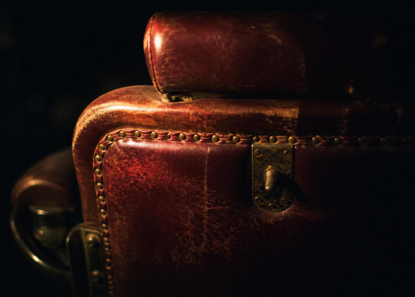 The back of a worn oxblood leather barber chair under warm light