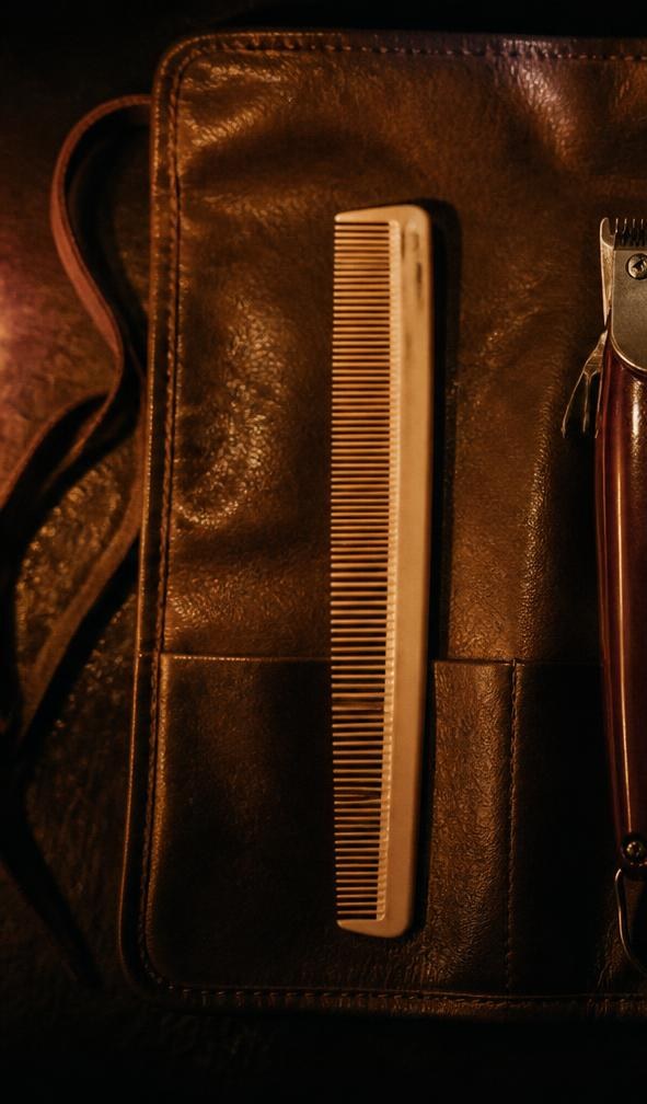 A comb laid in a leather tool roll under a low lamp